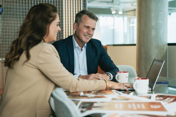 En kvinde og en mand der sidder og kigger i en laptop